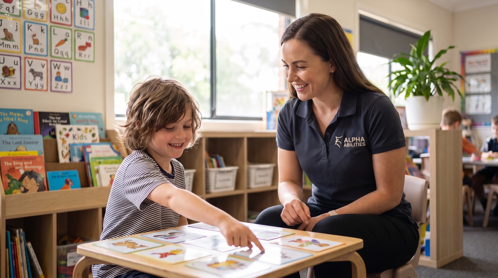 An Alpha Abilities therapist working through picture cards with a smiling child at a classroom table